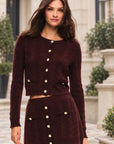 LoveShackFancy Eugenie Cardigan in cinnabar, on model in a townhouse courtyard