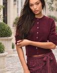 LoveShackFancy Cameryn Cardigan in roasted pomegranate, on model in a townhouse courtyard
